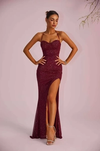 Detail of elegant sequined burgundy evening gown with halter neck and high leg slit