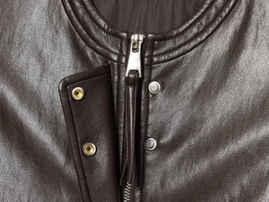 Close-up of dark brown PU leather collar with silver metal zipper and snap button details