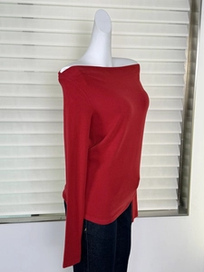 Détail d'un haut rouge à épaules dénudées et manches longues montrant la texture en tricot