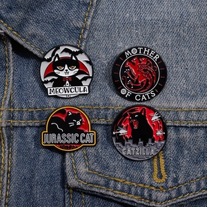 Set of 4 dark humor cartoon black cat enamel pins on a blue denim jacket pocket