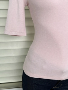 Detailed close-up of pink slim fit knit top sleeve and waist with denim jeans