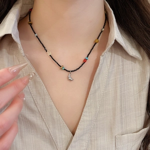 Detail of beaded necklace with colorful stones and silver croissant pendant on a linen shirt