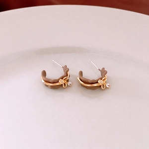 Detail of vintage 18k gold plated C-shape earrings with a bow and zircon inlay