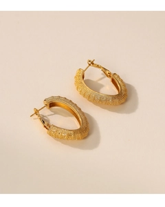 Detail of gold oval earrings with a frosted grainy texture and retro metal finish