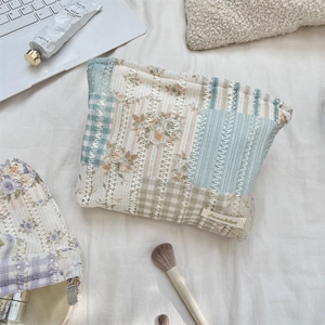 Detail view of the floral quilted makeup bag with hollow lace design and metal zipper