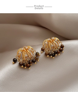 Macro detail of vintage gold fringe earrings with zircon and tiger eye beads on satin