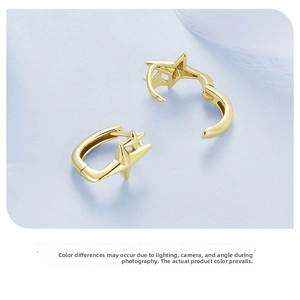 Macro shot of stylish gold star-shaped hoop earrings on a light blue textured surface