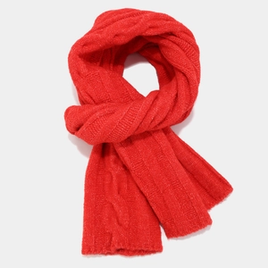 Close-up of bright red cable-knit wool scarf showing thick 3D braided texture and pattern