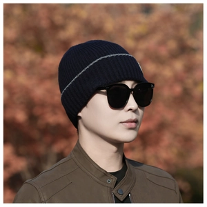 Detail view of a navy knit beanie with gray stripes on a male model in autumn