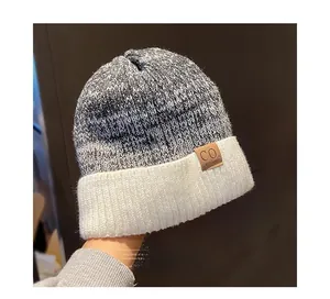 Detail of knit beanie with brown leather logo patch and white ribbed folded cuff