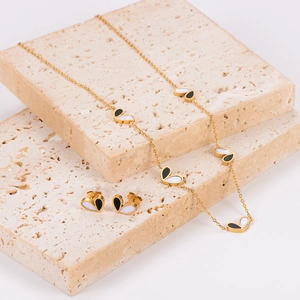 Two-tone heart jewelry set with gold necklace and stud earrings on stone blocks