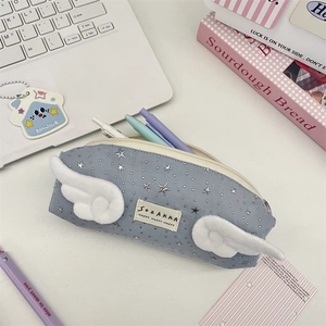 Detailed blue pencil case with plush wings and star patterns on a desk workspace
