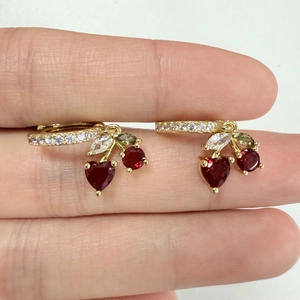 Detail of gold cherry earrings featuring red heart gems and tiny white zircons on hoops