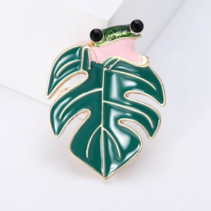 Detail of frog and monstera leaf brooch with green enamel and black rhinestones