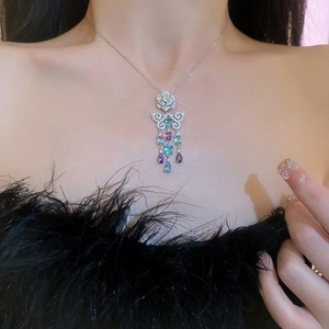 Dettaglio della collana floreale in argento con gemme colorate e nappe sulla modella