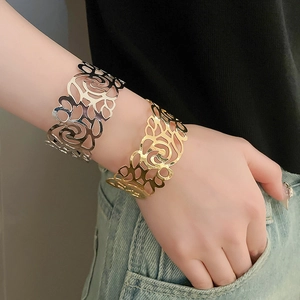 Close-up of gold and silver open bangles with intricate cutout rose floral patterns