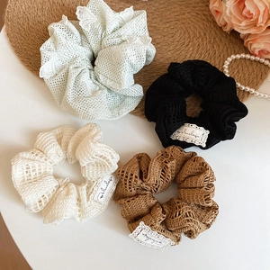 Gros plan de chouchous au crochet en menthe, crème et marron avec étiquettes en dentelle