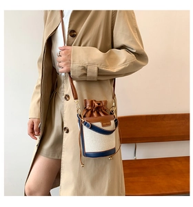 Detail of canvas bucket bag with brown leather trim and drawstring closure on model