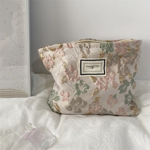 Détail du tissu jacquard à fleurs en relief sur la grande trousse de maquillage chic