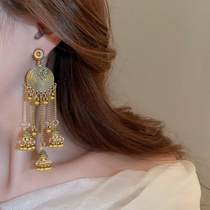Detailed view of vintage gold tassel earrings with intricate floral cluster on model