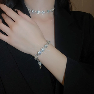 Close-up of sparkling rhinestone necklace and bracelet set on a model in a black suit
