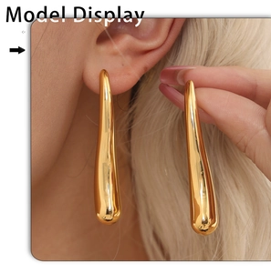 Close-up of model wearing polished gold teardrop hollow earrings with sleek metallic finish