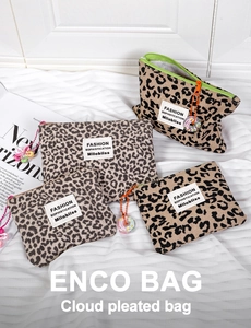 Pochette in tela leopardata di varie dimensioni con ciondoli decorativi su tessuto bianco