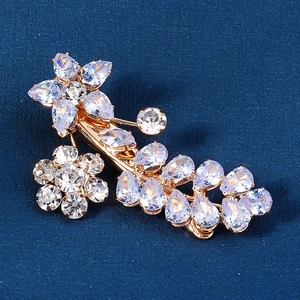 Detailed close-up of golden floral hair clip inlaid with white cubic zirconia crystals