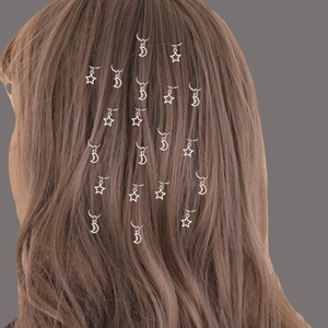 Detailed view of silver star and moon hair rings styled on long braided hair