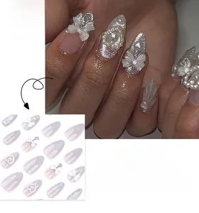 Détail de faux ongles amande avec nœuds 3D, perles et dégradé pailleté argenté élégant
