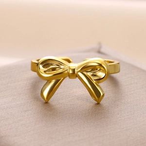 Macro shot of polished gold bow ring on a textured champagne display stand