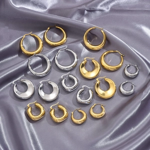 Macro detail of various chunky hoop earrings in gold and silver on silk fabric