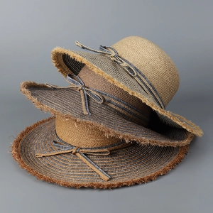 Stacked raffia sun hats featuring frayed edges and decorative rope bows for summer