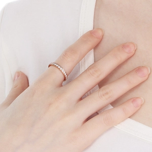 Close-up of a rose gold eternity ring with small diamonds worn on the index finger