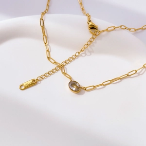Detail view of gold lobster clasp and K18 engraved tag on the square link chain
