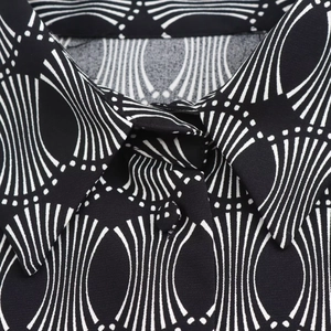 Detailed view of shirt collar with white geometric patterns on black fabric texture