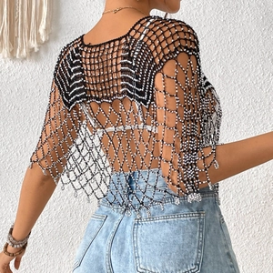 Détail de châle en maille crochet noire avec pompons perlés blancs et style bohème