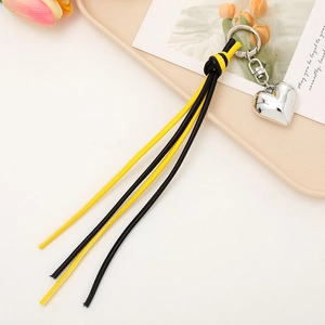 Close-up of heart-shaped silver keychain with yellow and black woven tassel accessory
