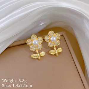 Detailed view of gold flower stud earrings with white pearl and sparkling zircon stones
