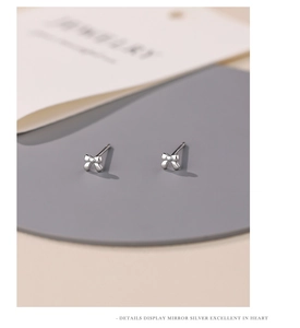 Macro shot of polished silver bow earrings with a smooth mirror finish for women