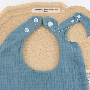 Detail of adjustable snaps and soft cotton gauze texture on a blue baby bib