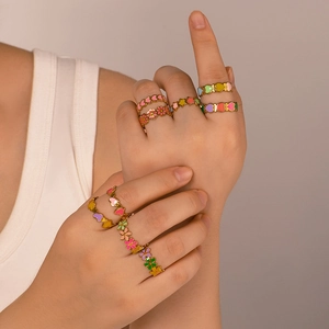 Set aus bunten Herz- und Blumenringen aus Edelstahl an der Hand eines Models