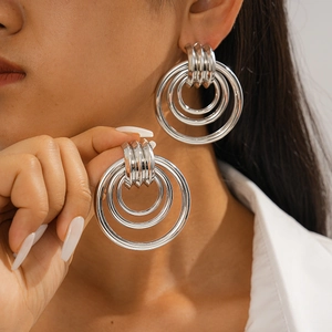 Close-up of geometric hollow concentric silver hoop earrings worn by a female model