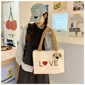 Close-up of white plush tote bag with LOVE embroidery and cute dog charm in cafe
