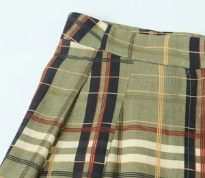 Gros plan du pantalon en lin à carreaux verts montrant les plis et la texture du tissu