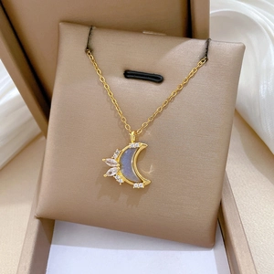 Detailed macro view of gold-tone moon pendant with sparkling crystals on a beige cushion
