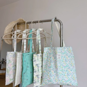 Detail showing various patterns like floral, grid, and animal prints on canvas tote bags