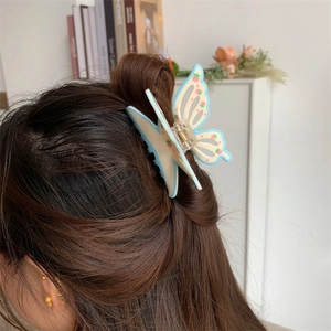 Detail of blue butterfly hair claw clip with strawberry print used in a half-up hairstyle