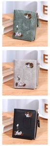 Three embroidered cat wallets in green, grey, and black on a wooden background