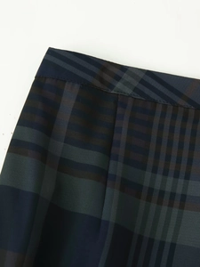 Détail macro du tissu à carreaux et des coutures de taille sur le pantalon écossais